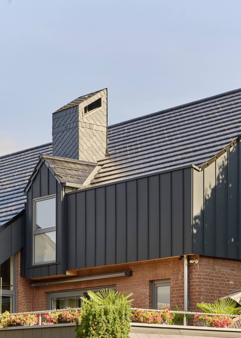 Wohnhaus mit dunkler Fassadenverkleidung und ausgebautem Dachgeschoss